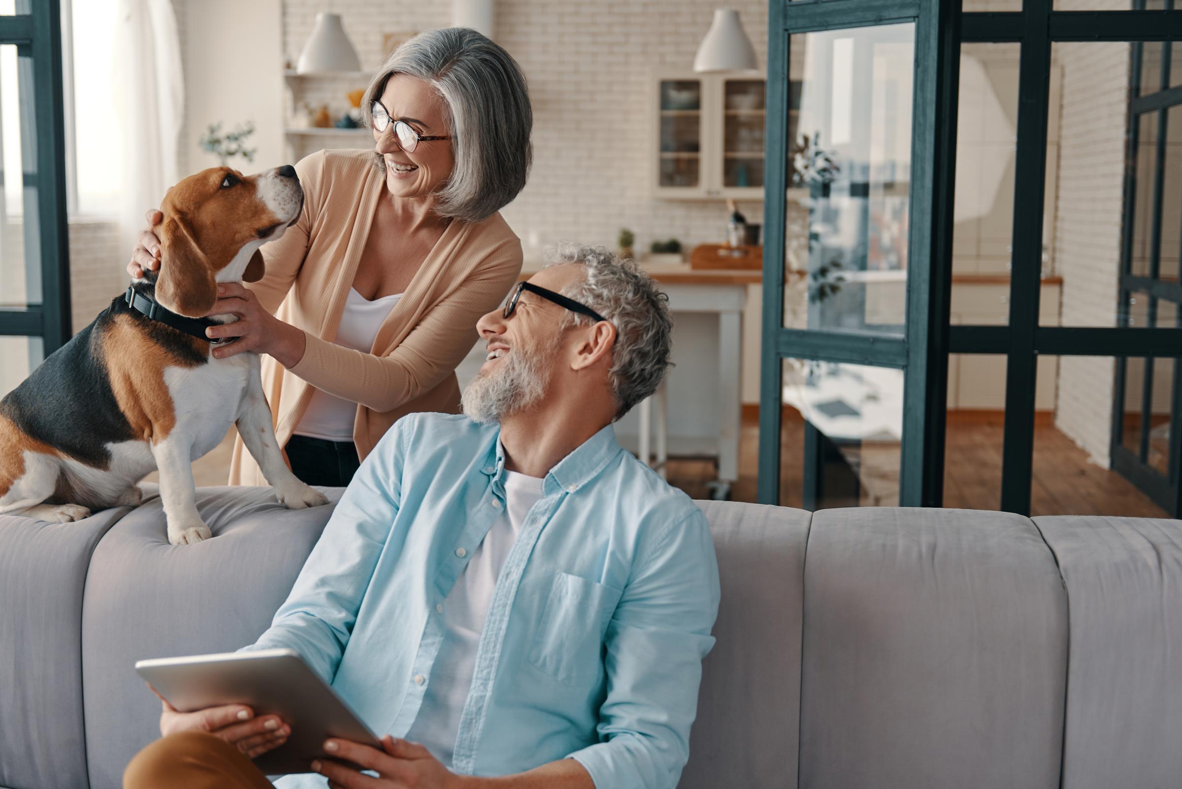 Older couple embrace their dog at home.