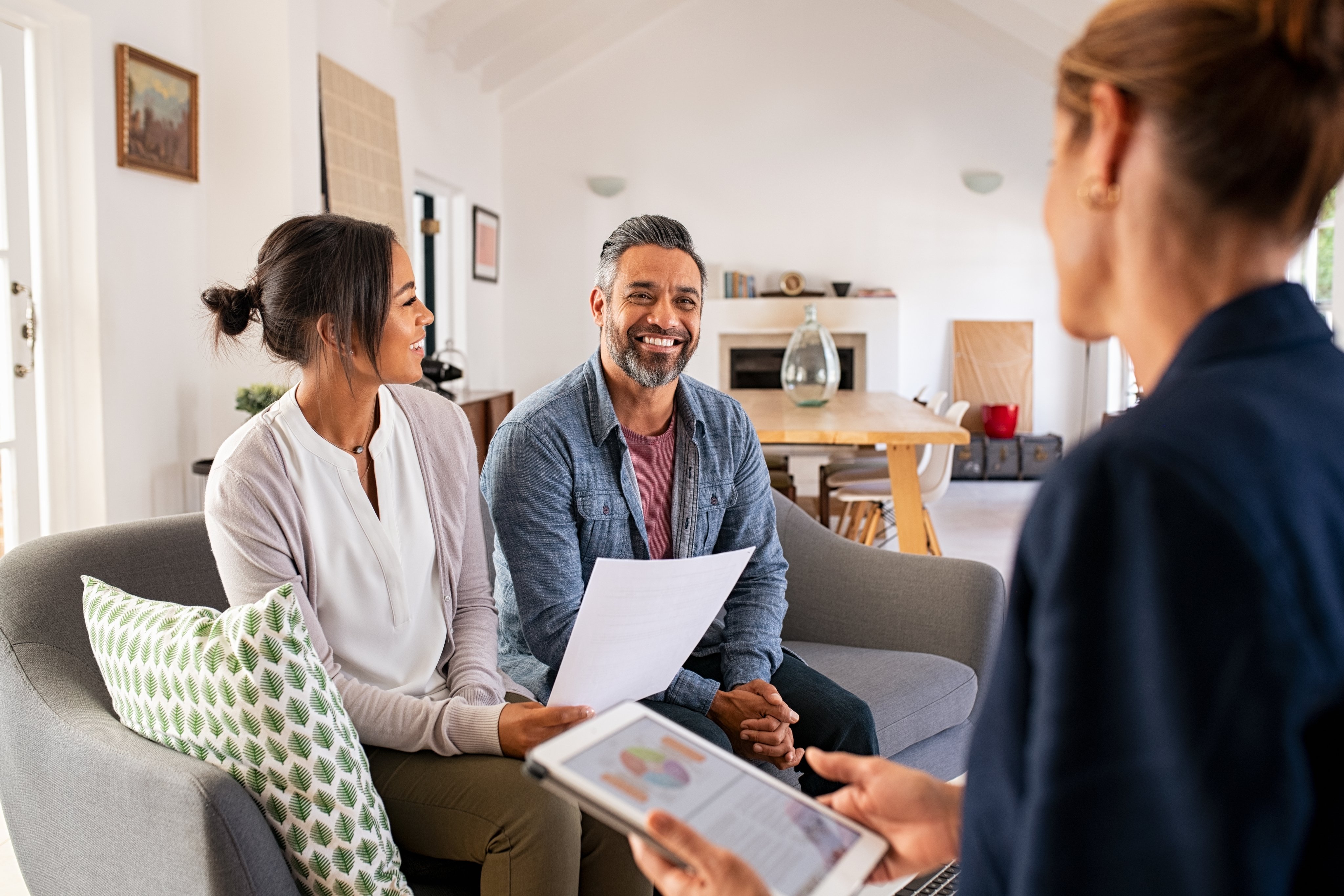 Happy mature couple discussing investments with financial broker during meeting at home.