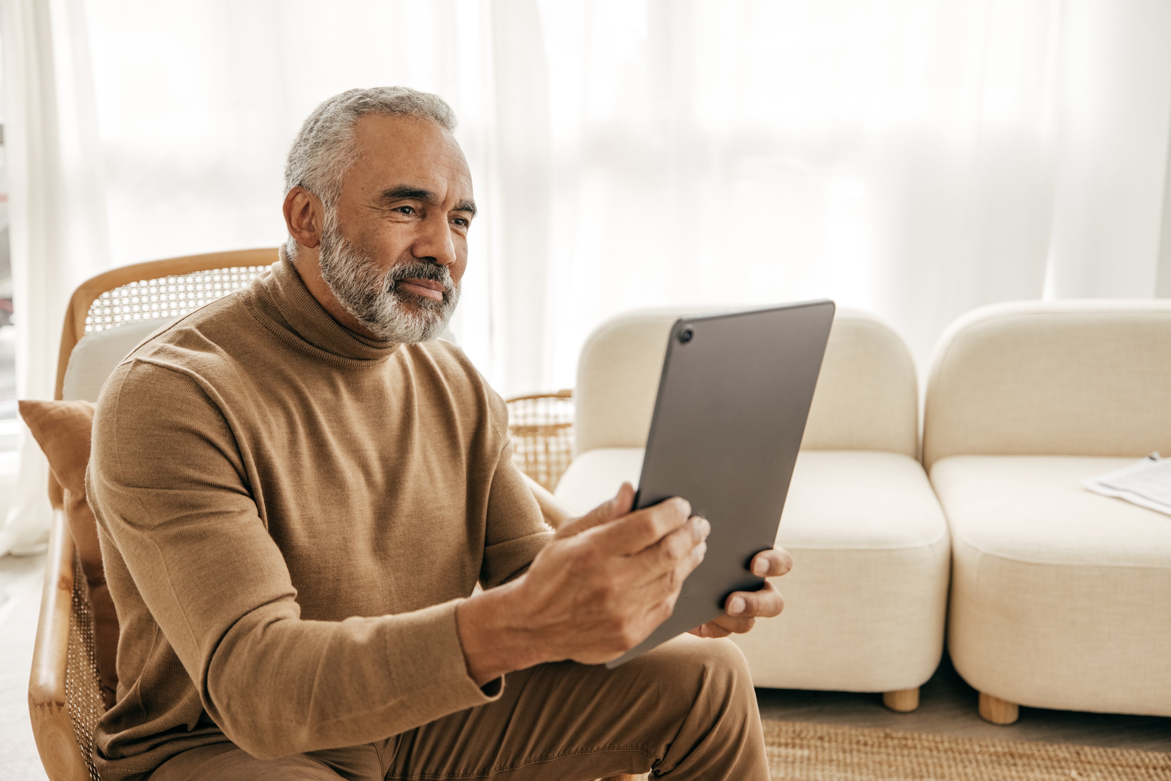 Older man using an ipad while sitting at home