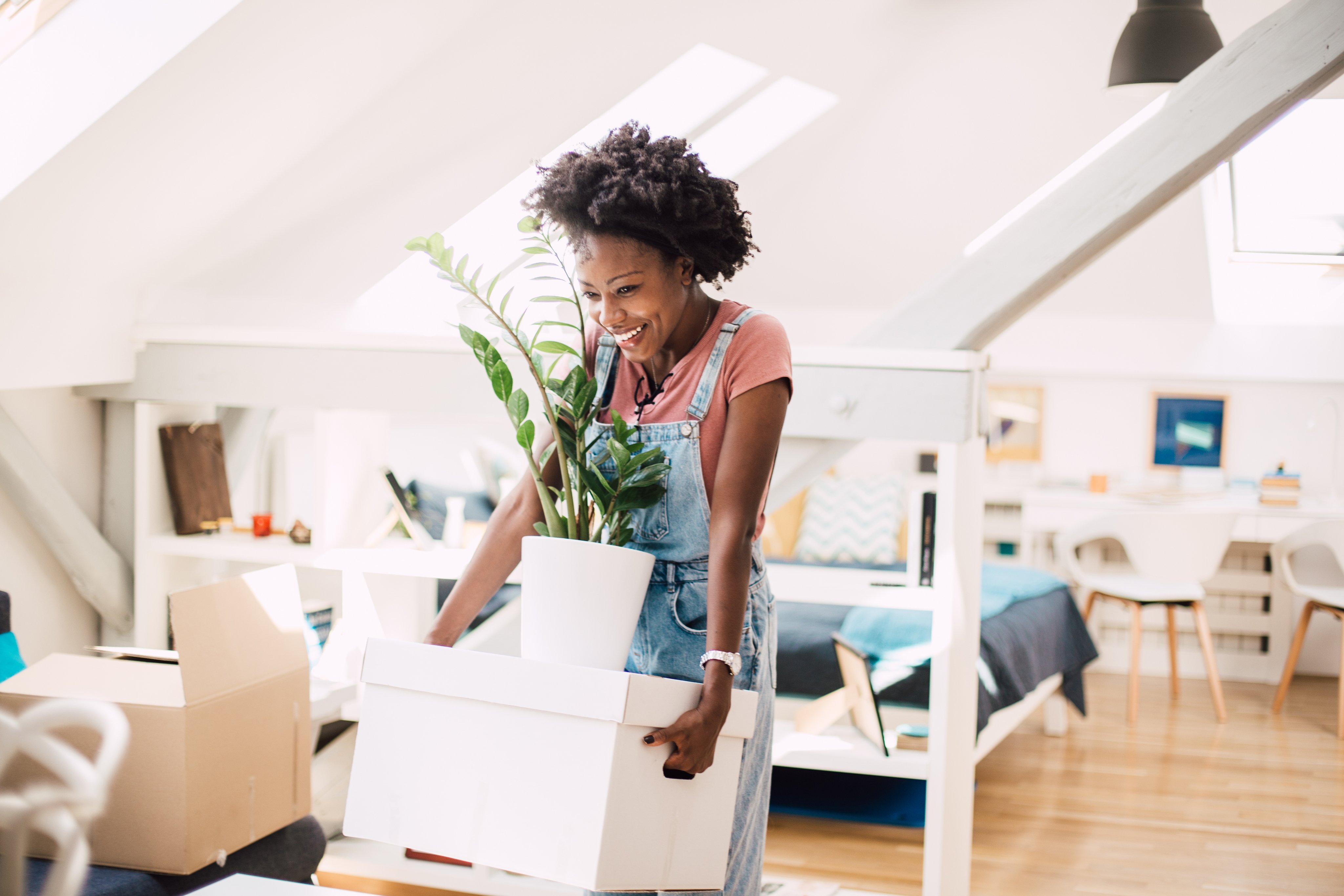 a young woman moves plants and packing boxes