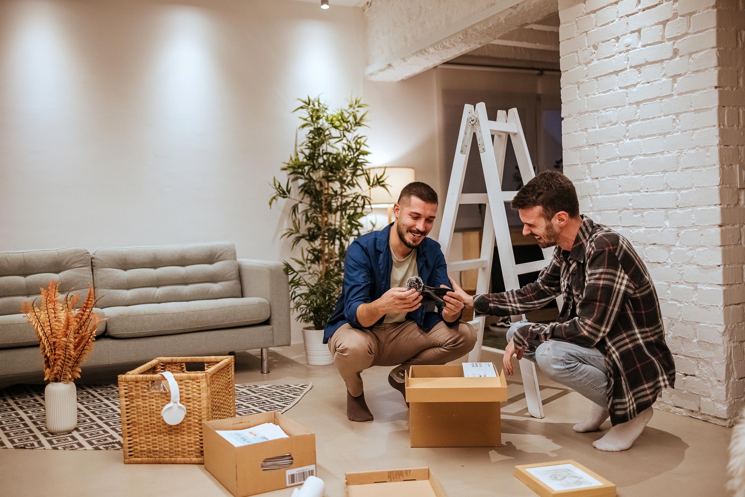 Couple unpacking. One man holds a glove and the other has his hand on partner's arm.