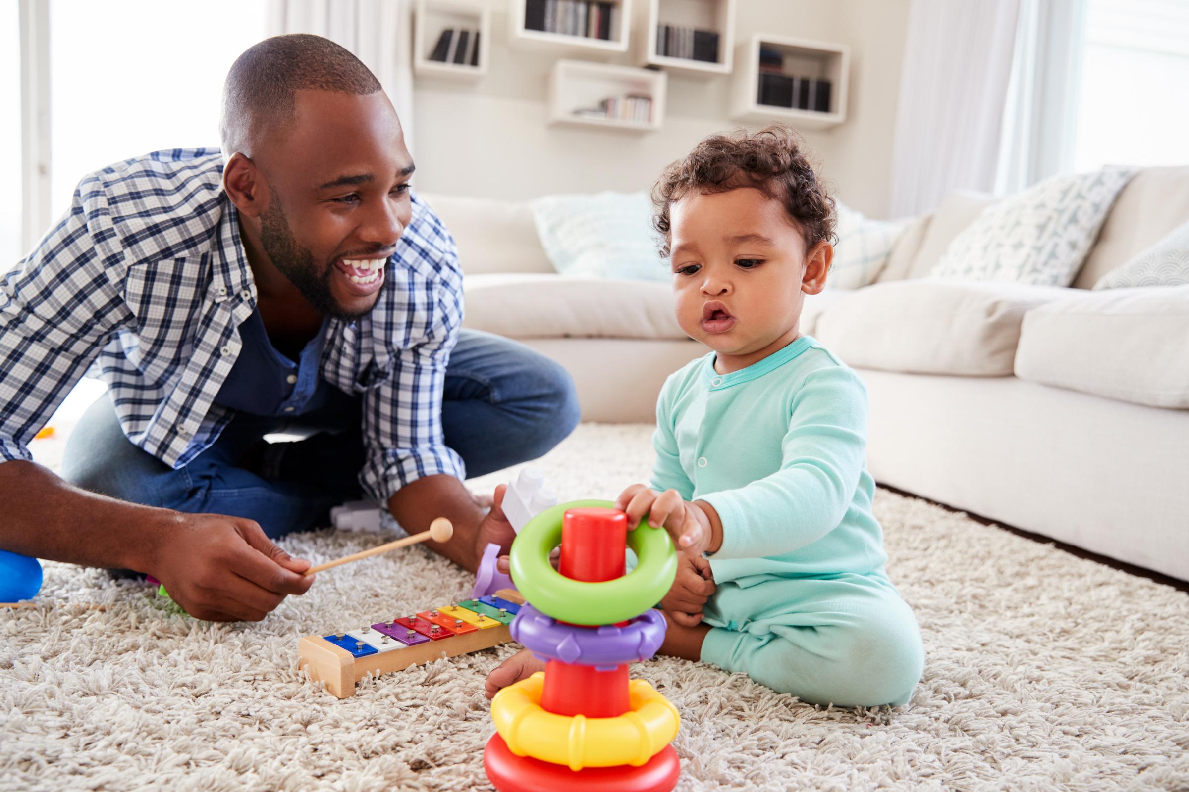 Dad and toddler son playing on floor at home.