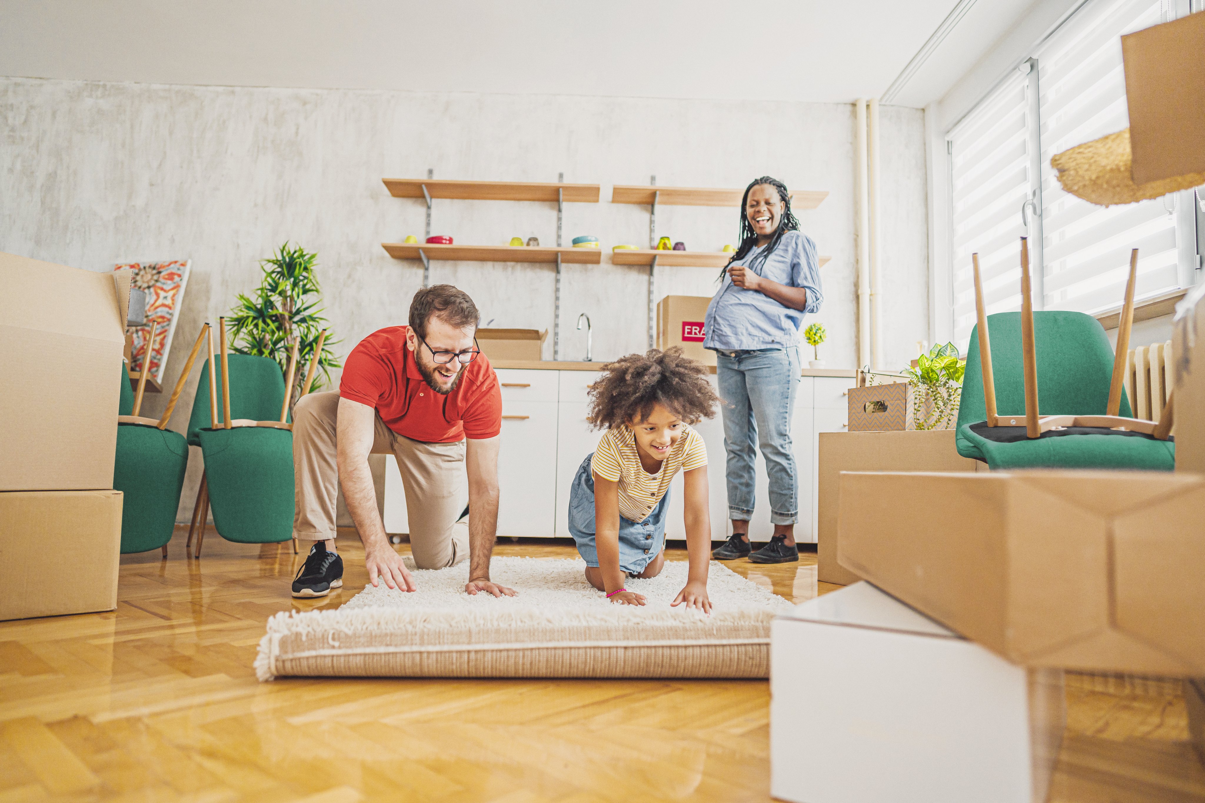Family unpacking in their new home by rolling out a living room carpet