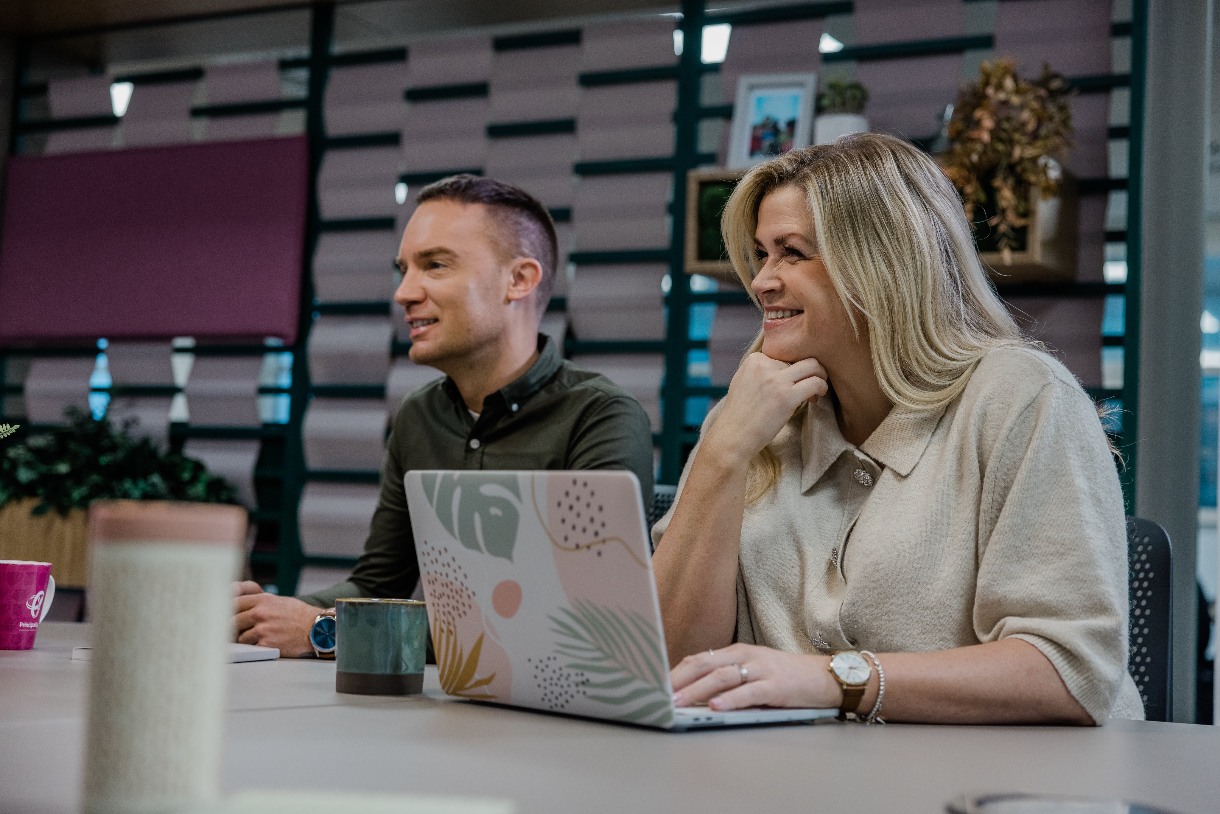 A woman on a laptop sat next to her male colleauge 