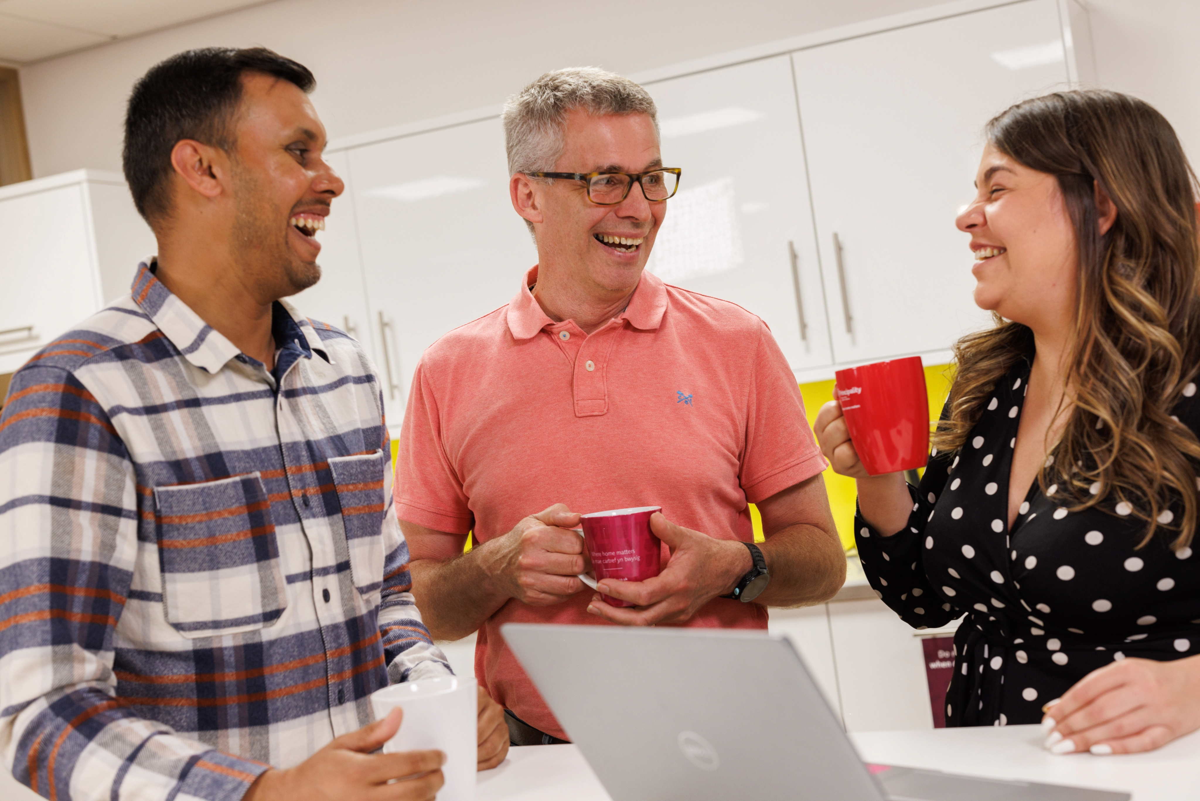 three colleague chatting in the kitchen drinking tea