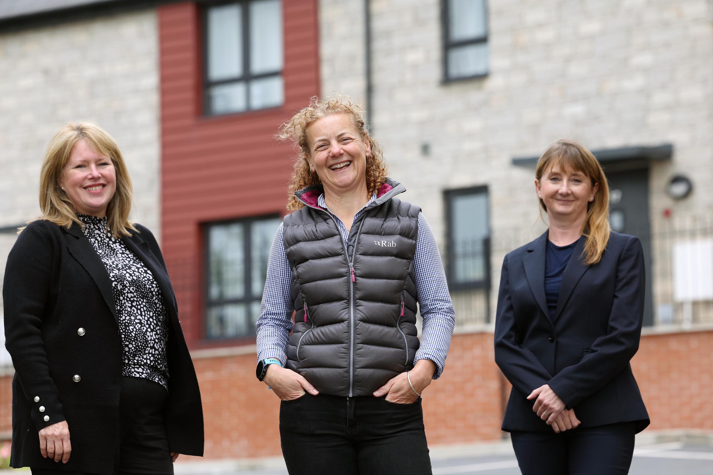 Three women stand in front of new home