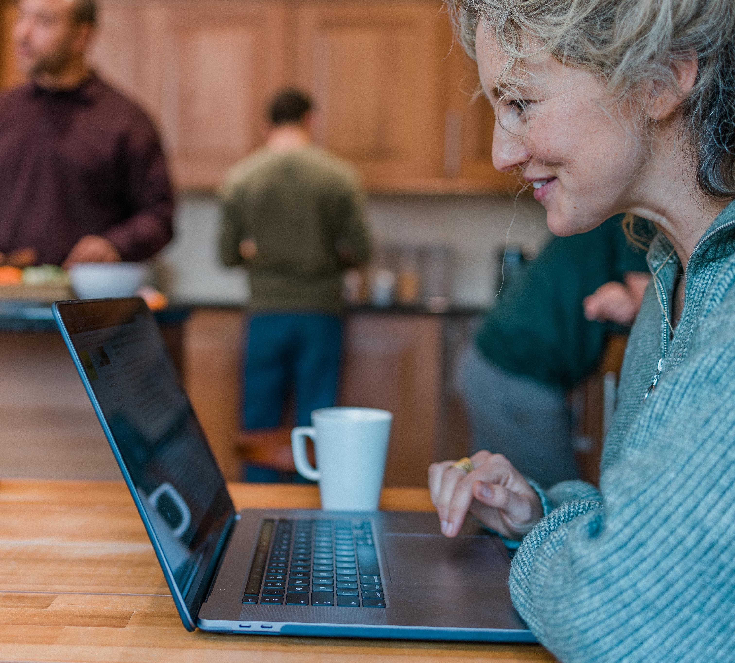 Woman sat at kitchen table on her laptop