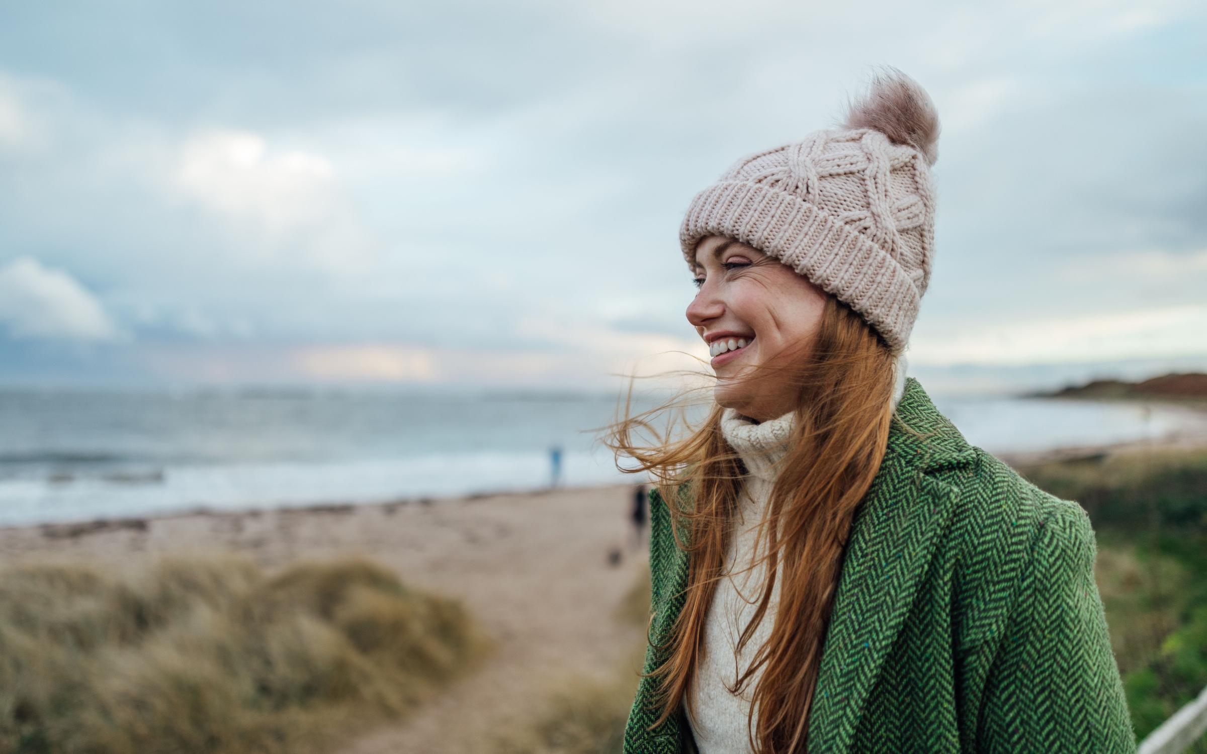  a young female adult smiling whilst on a beach walk 