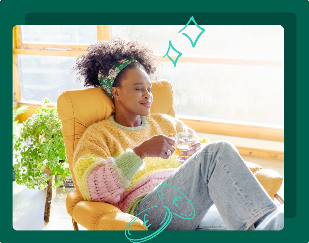 Young woman sits at home contently while sipping at drink
