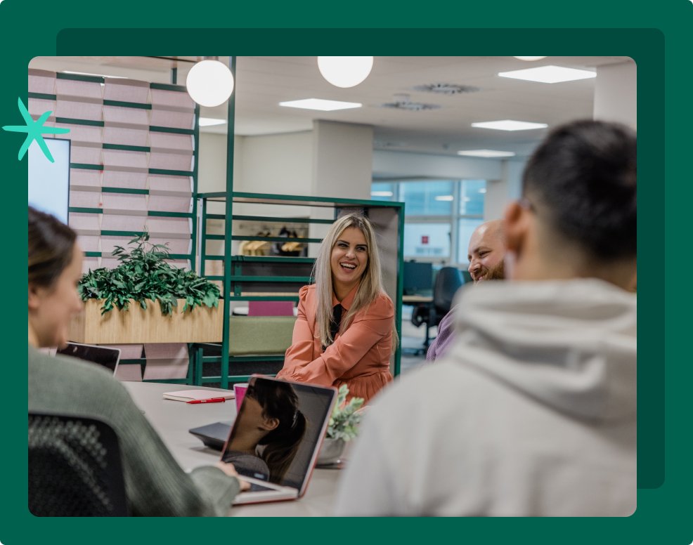 A women smiles at her co-workers in the middle of an office.