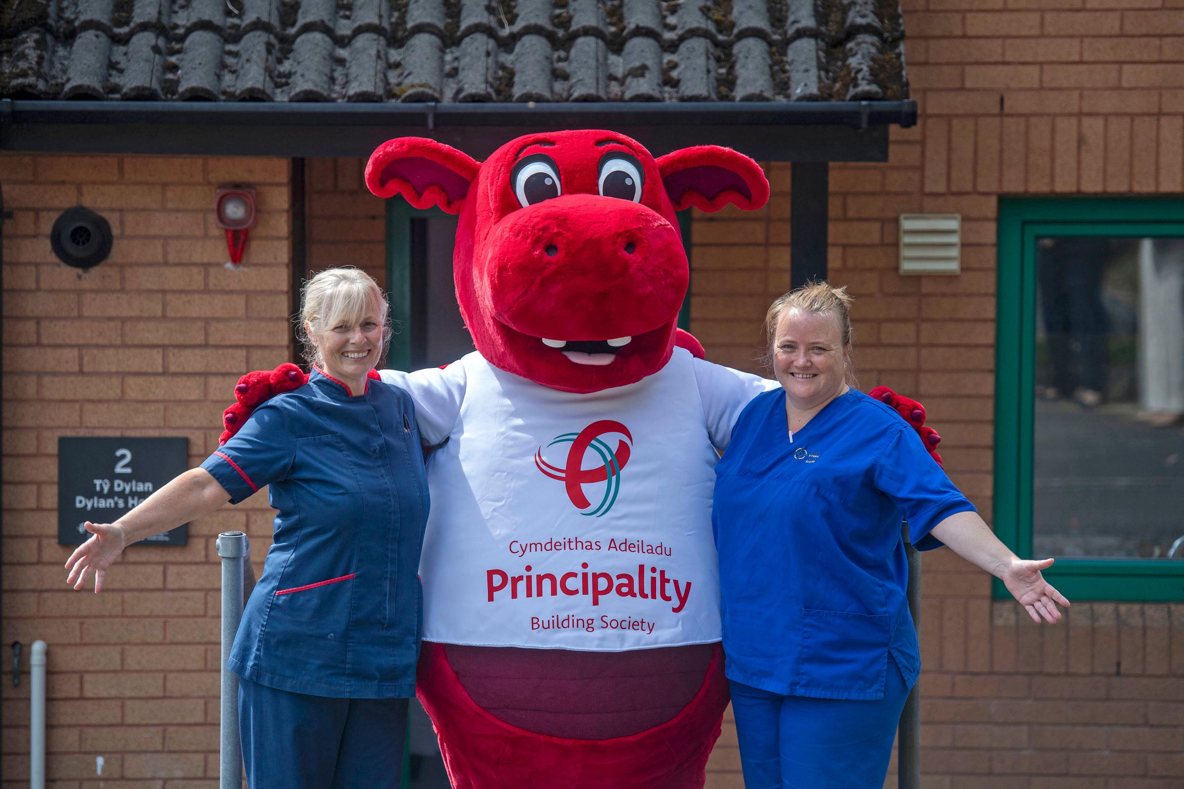 Principality Building Society mascot Dylan the Dragon outside Cwtsh Clos with Swansea Healthboard Nurses