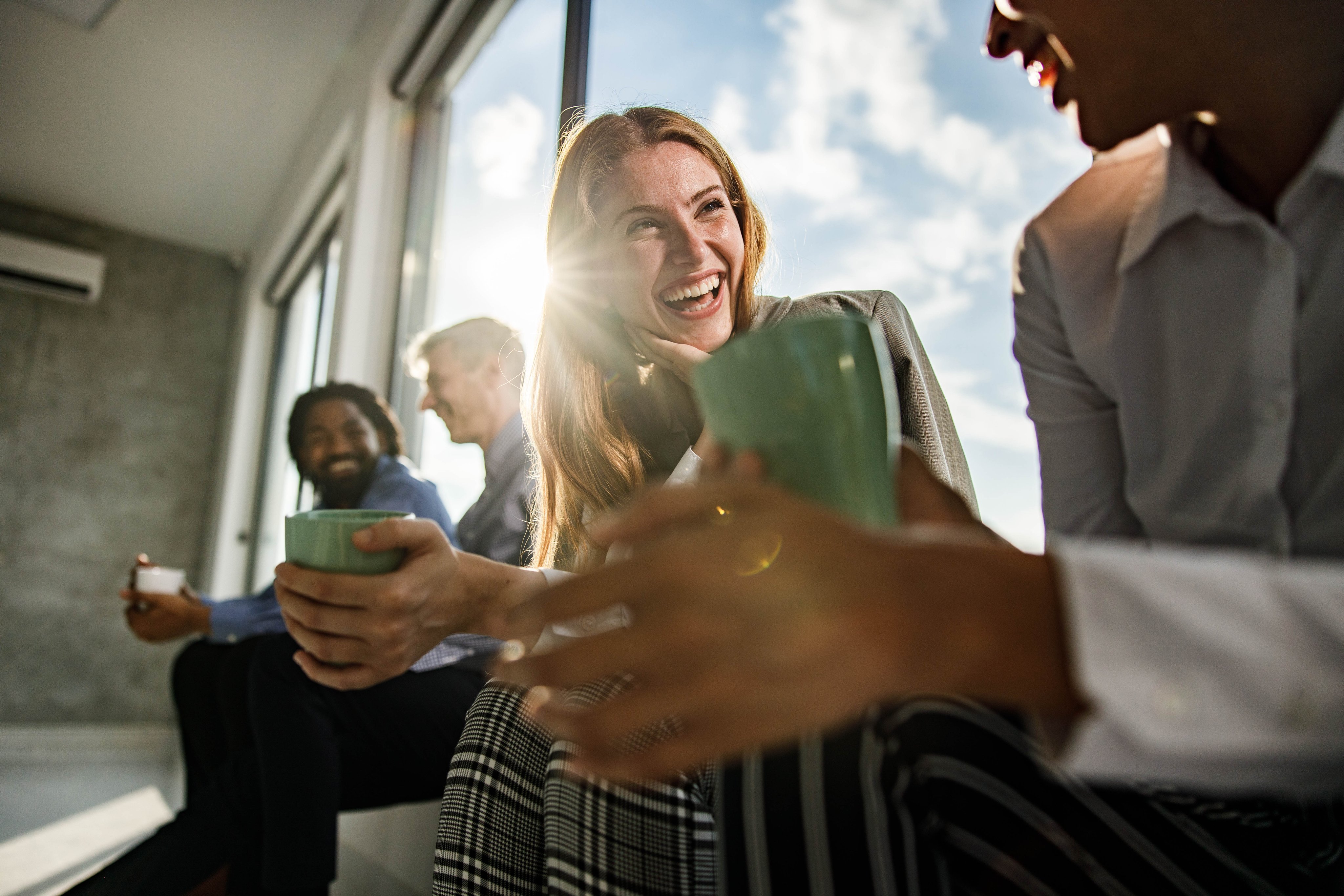  oedolion ifanc yn eistedd o flaen ffenestr lachar