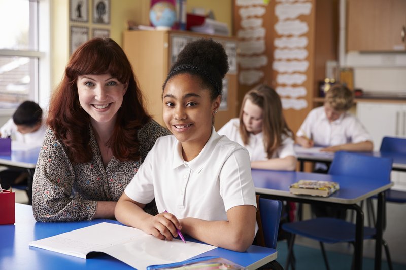 Primary school teacher and pupil in class looking to camera