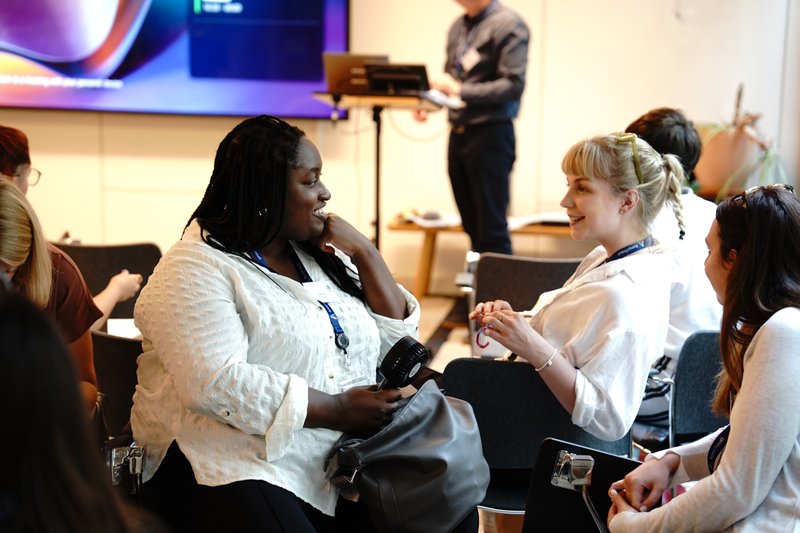 Three members of Anna Freud staff facing each other, smiling in conversation during a training session.