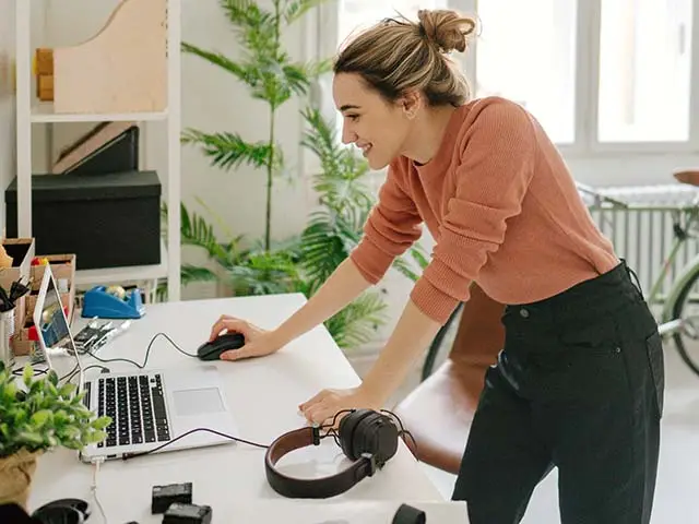 Frau arbeitet lächelnd, stehend am Laptop