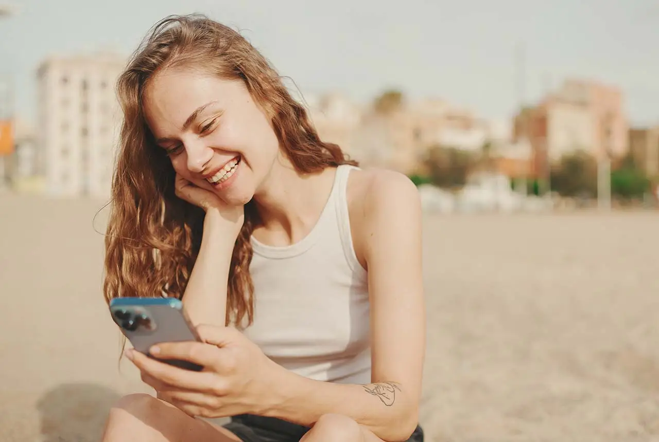 Frau am Strand mit Smartphone