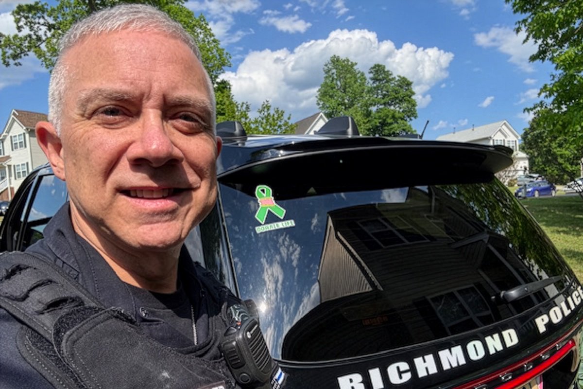 Tommy Obenrader, double organ donor, standing outside next to his police vehicle with a Donate Life sticker visible