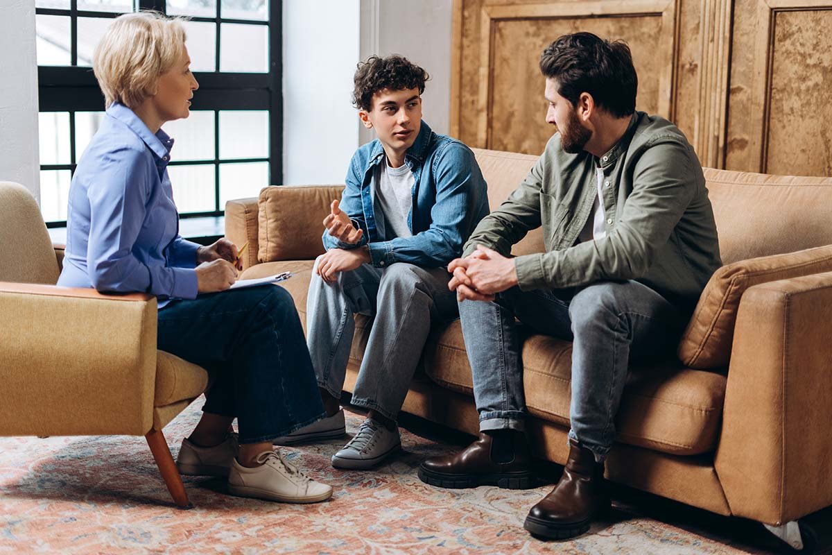 family sits together and talks to young teenage boy