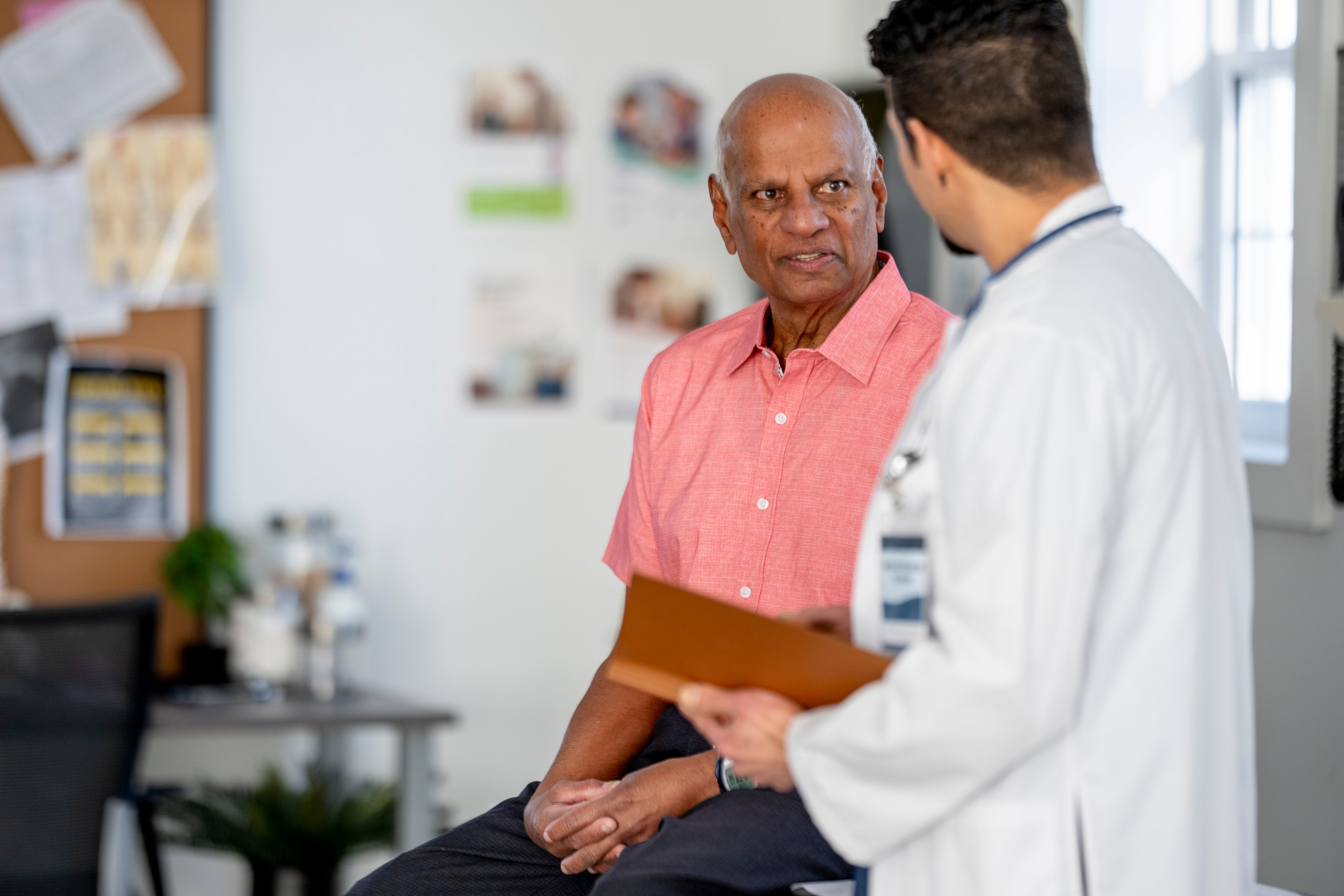 An older man talks with his doctor at a clinic appointment