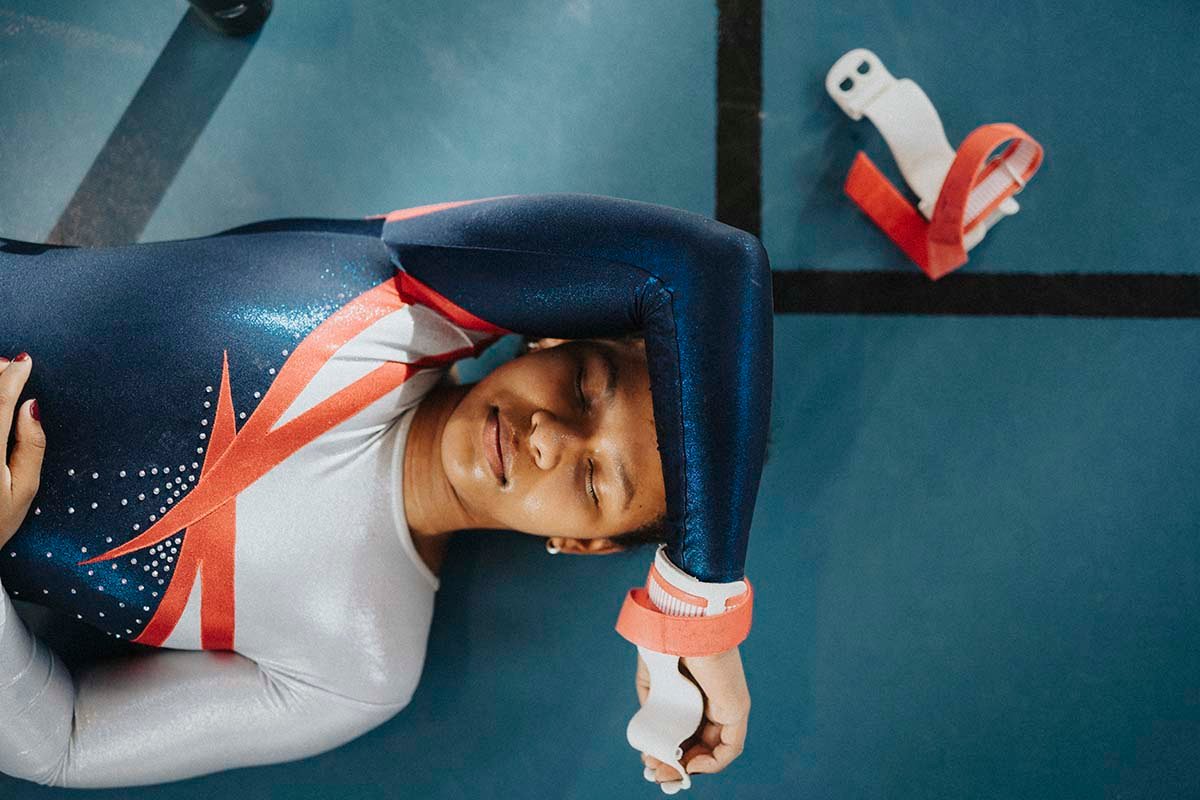 Young gymnast rests on mat