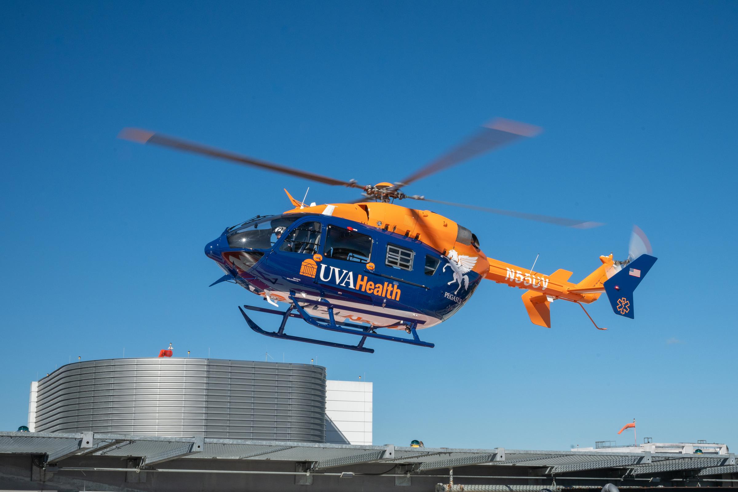An orange and blue helicopter in a clear sky