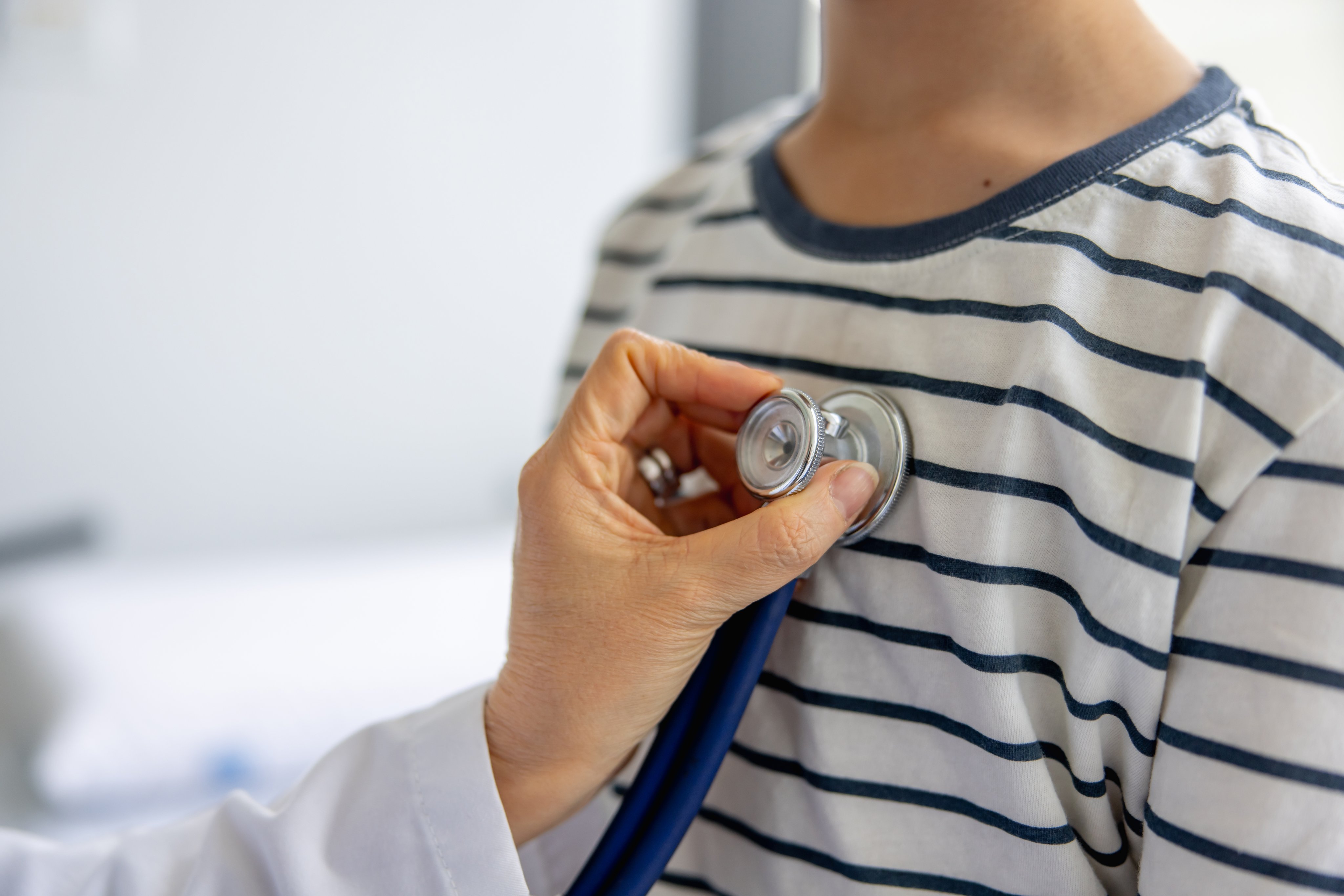 Pediatrician listening to boy's heart with a stethoscope.