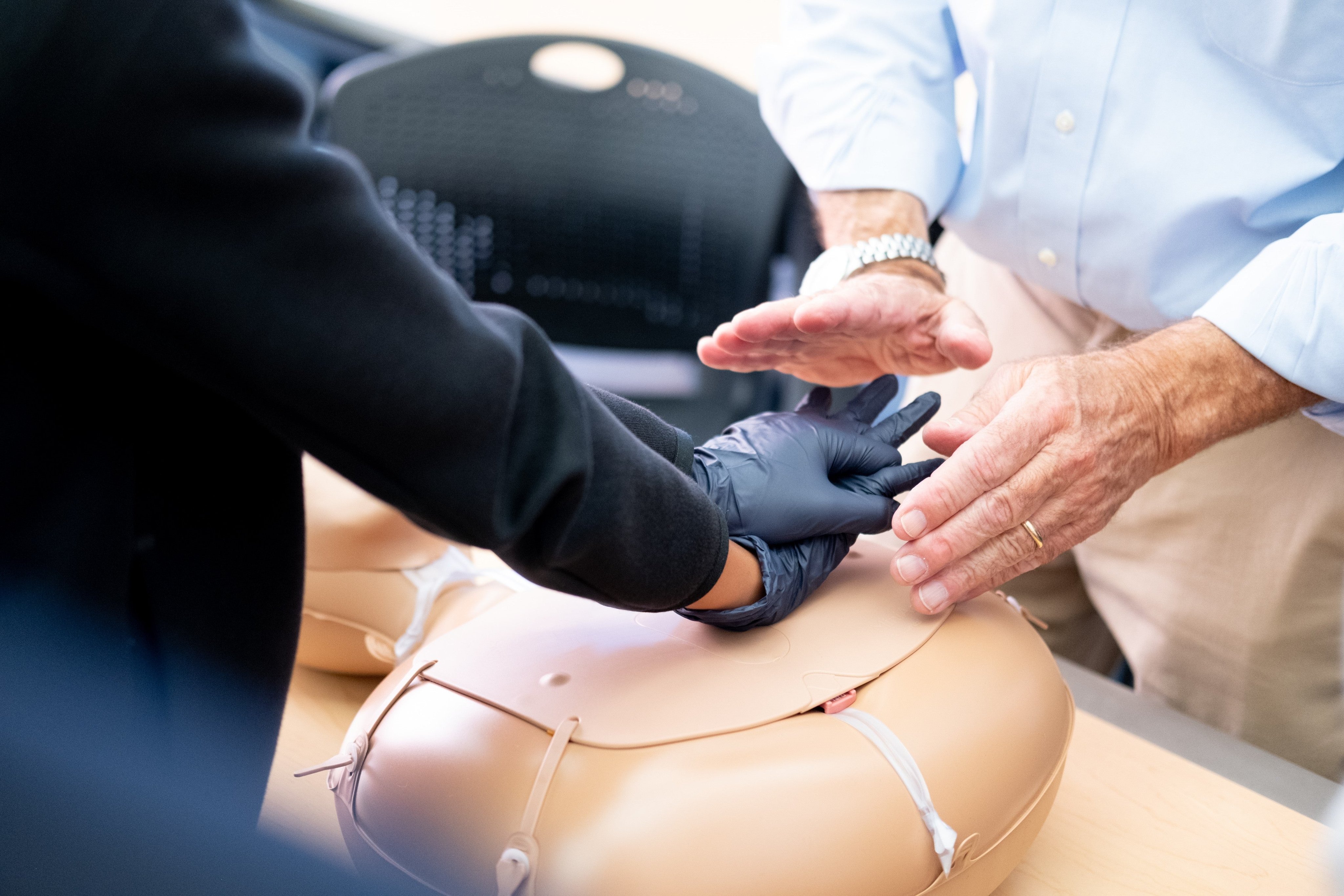 Instructor shows participant how to perform CPR on a dummy