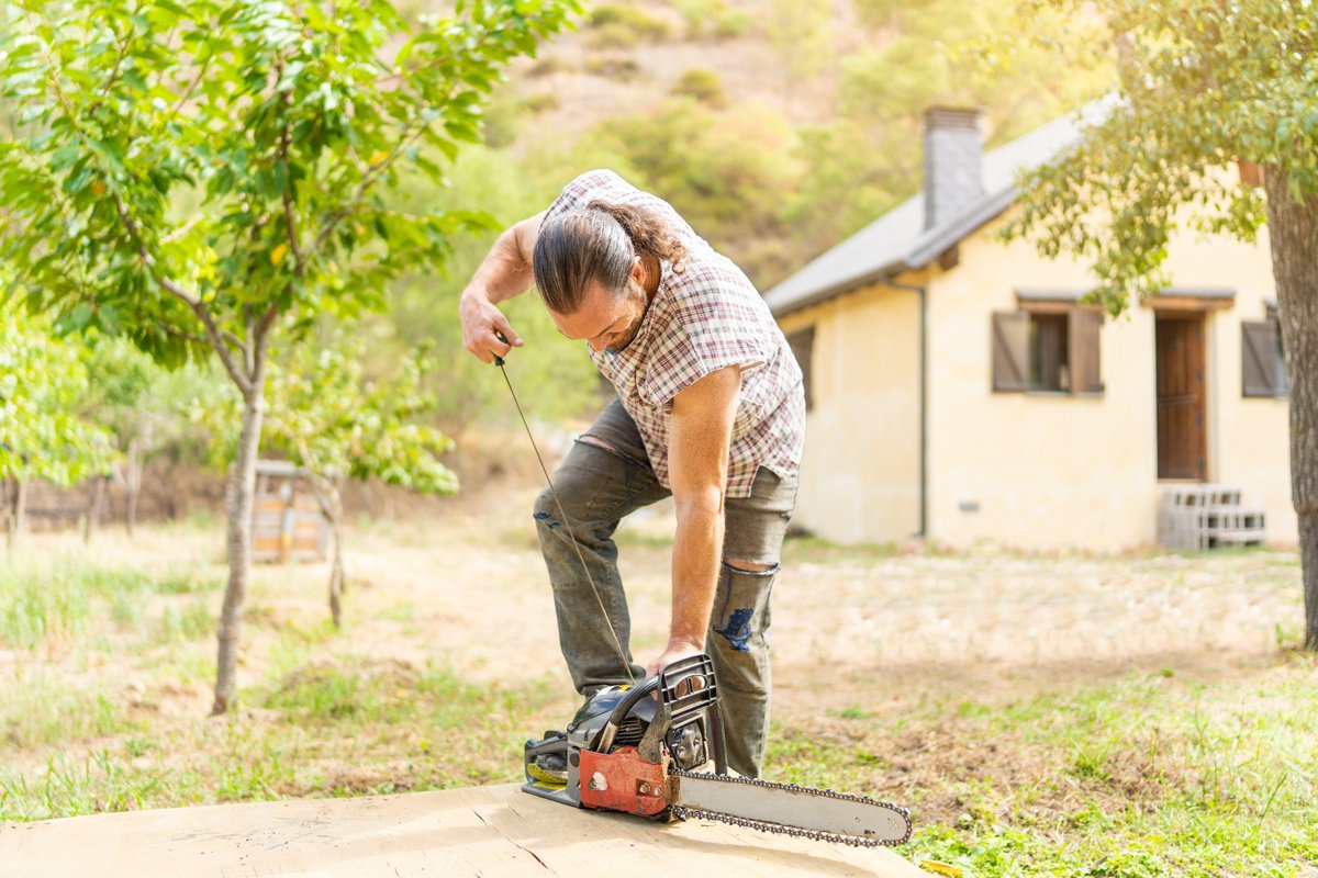 A man starting a chainsaw by pulling the cord.
