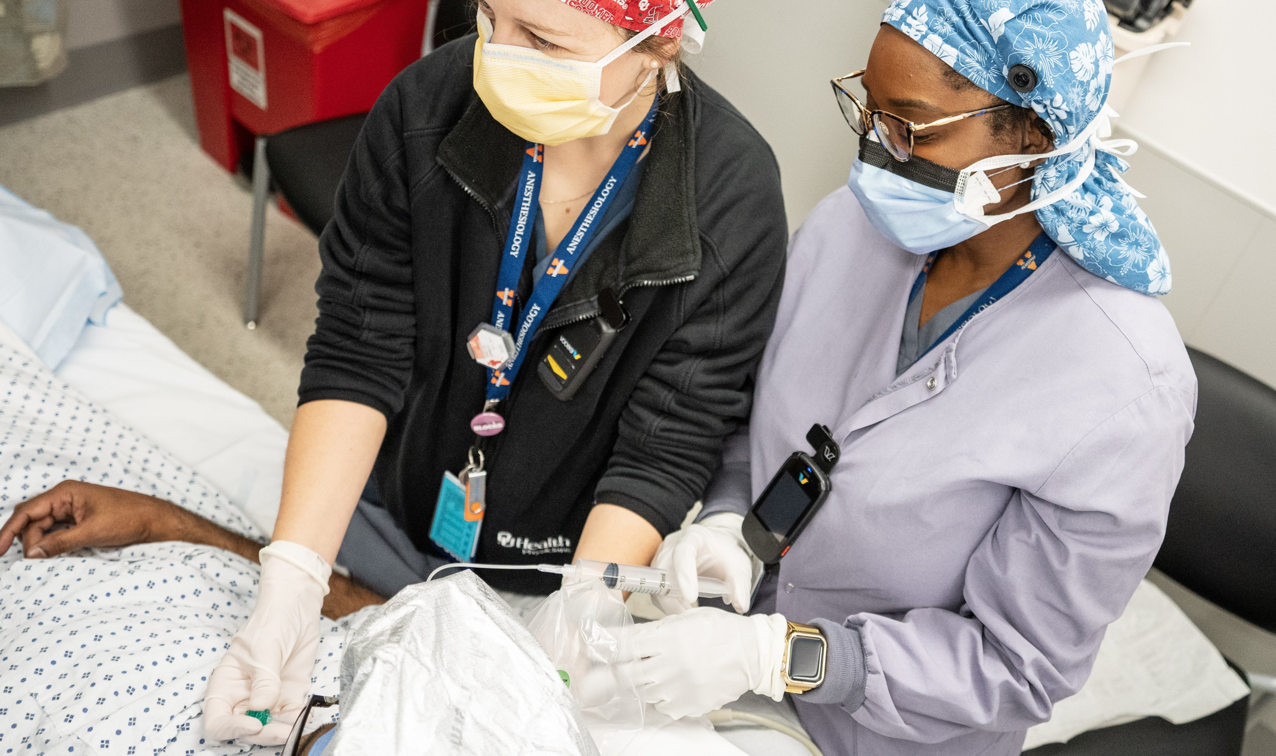 Two regional anesthesia providers performing a nerve block on a patient.