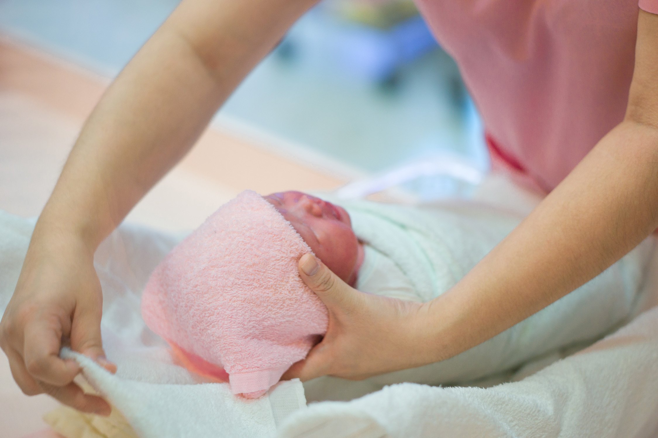 Mom puts swaddled baby down in bassinet