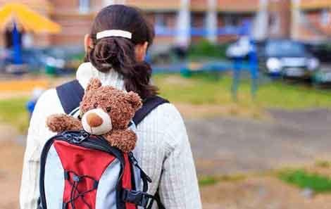 Girl with red backpack with teddy bear peeking up