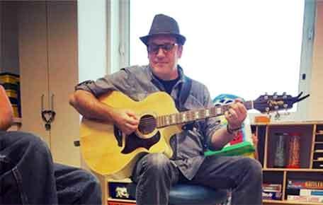 A child life visitor plays the guitar