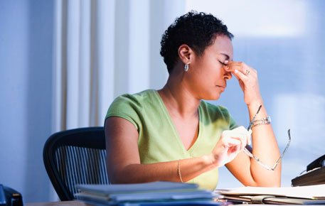 Woman pinches bridge of nose at work