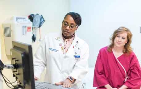 Doctor shows patient breast screening equipment ahead of procedure