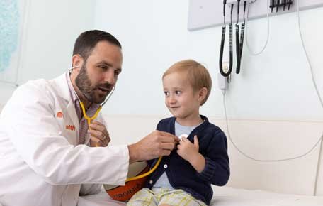 Doctor performs check-up on a young liver transplant recipient, a boy around 4 years old