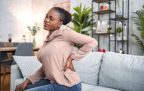 A woman winces and holds her back