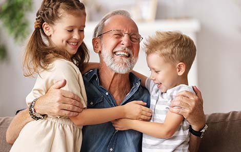 A grandfather hugs his grandchildren
