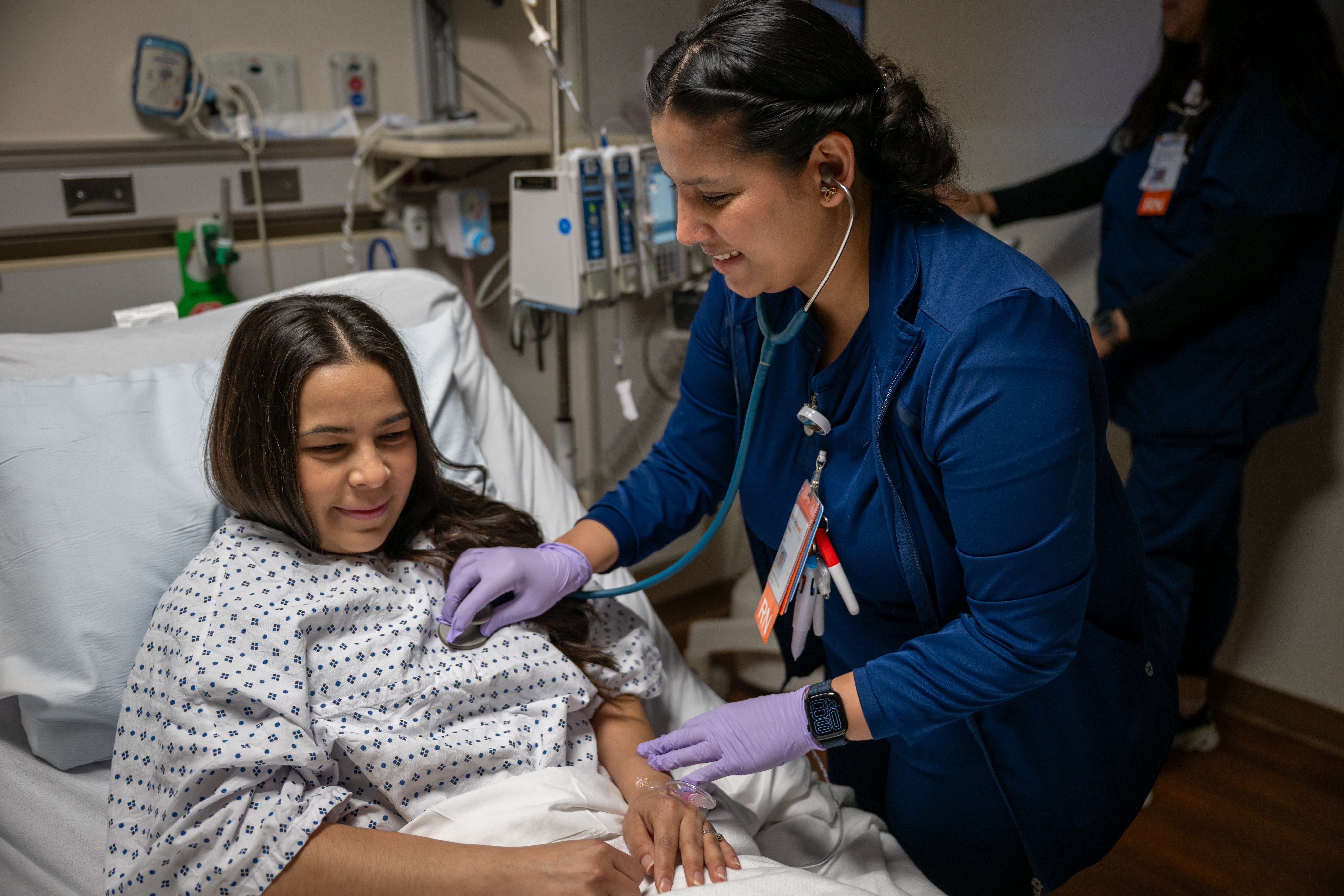 A nurse holding a stethoscope to a patient's chest