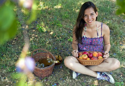 Young woman sits outdoors with basket of apples