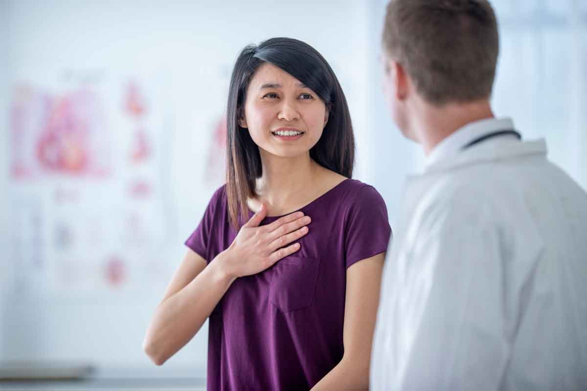 A Woman talking to a healthcare provider with her hand on her heart