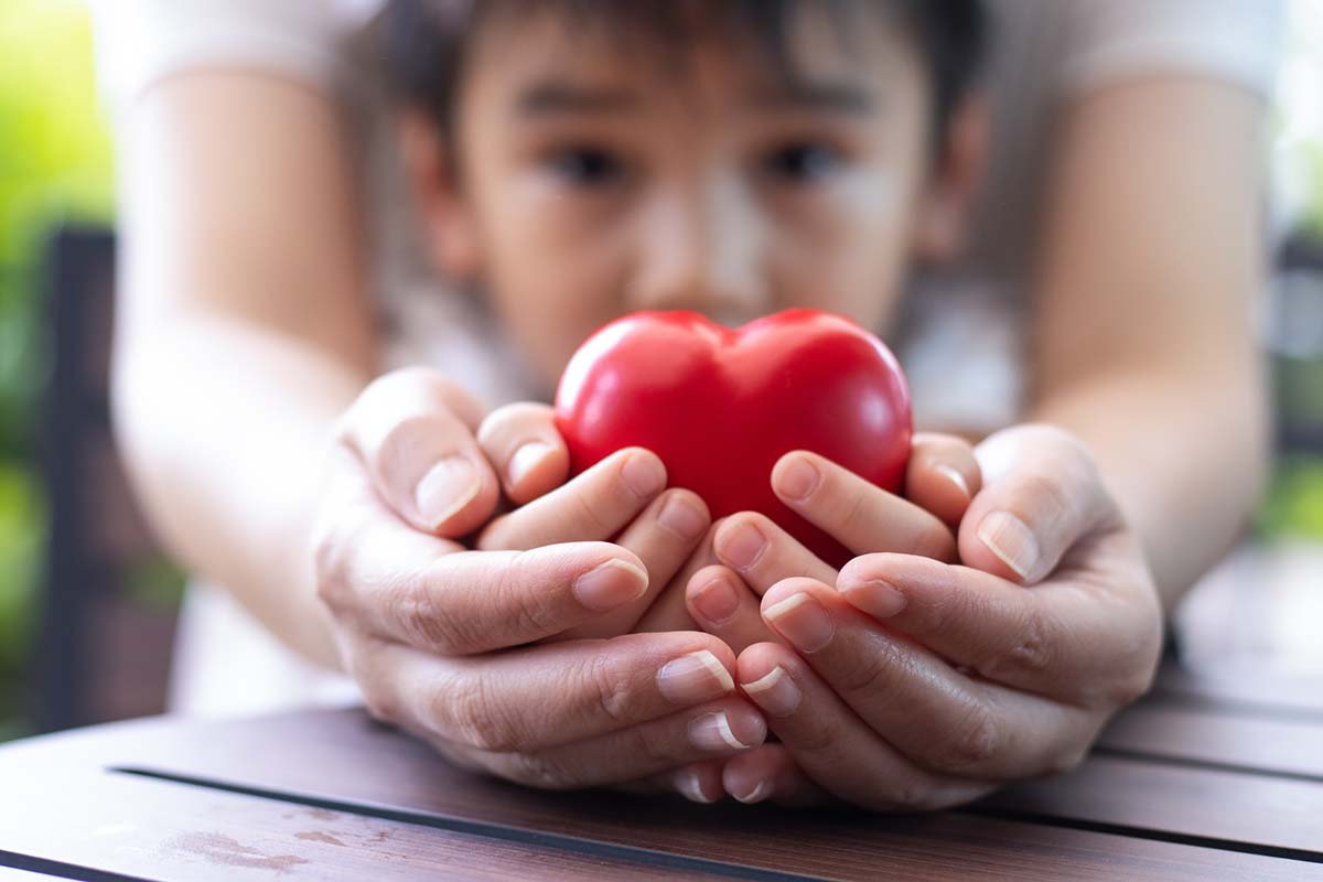 Child and adult holding a small heart in their hands