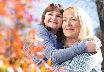 A woman holding a young girl and looking at leaves