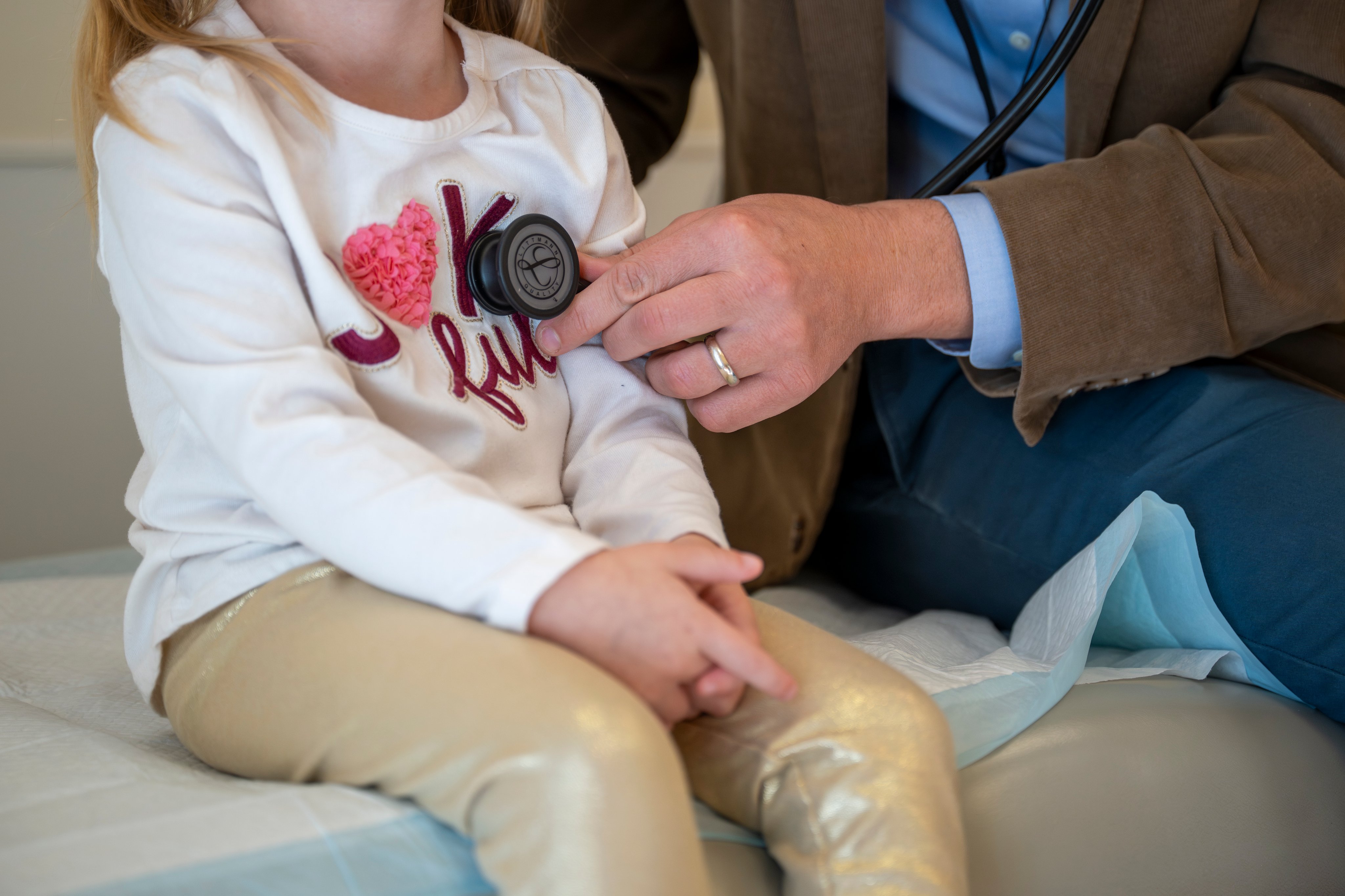 Pediatric cardiologist listens to patient's heart with stethoscope