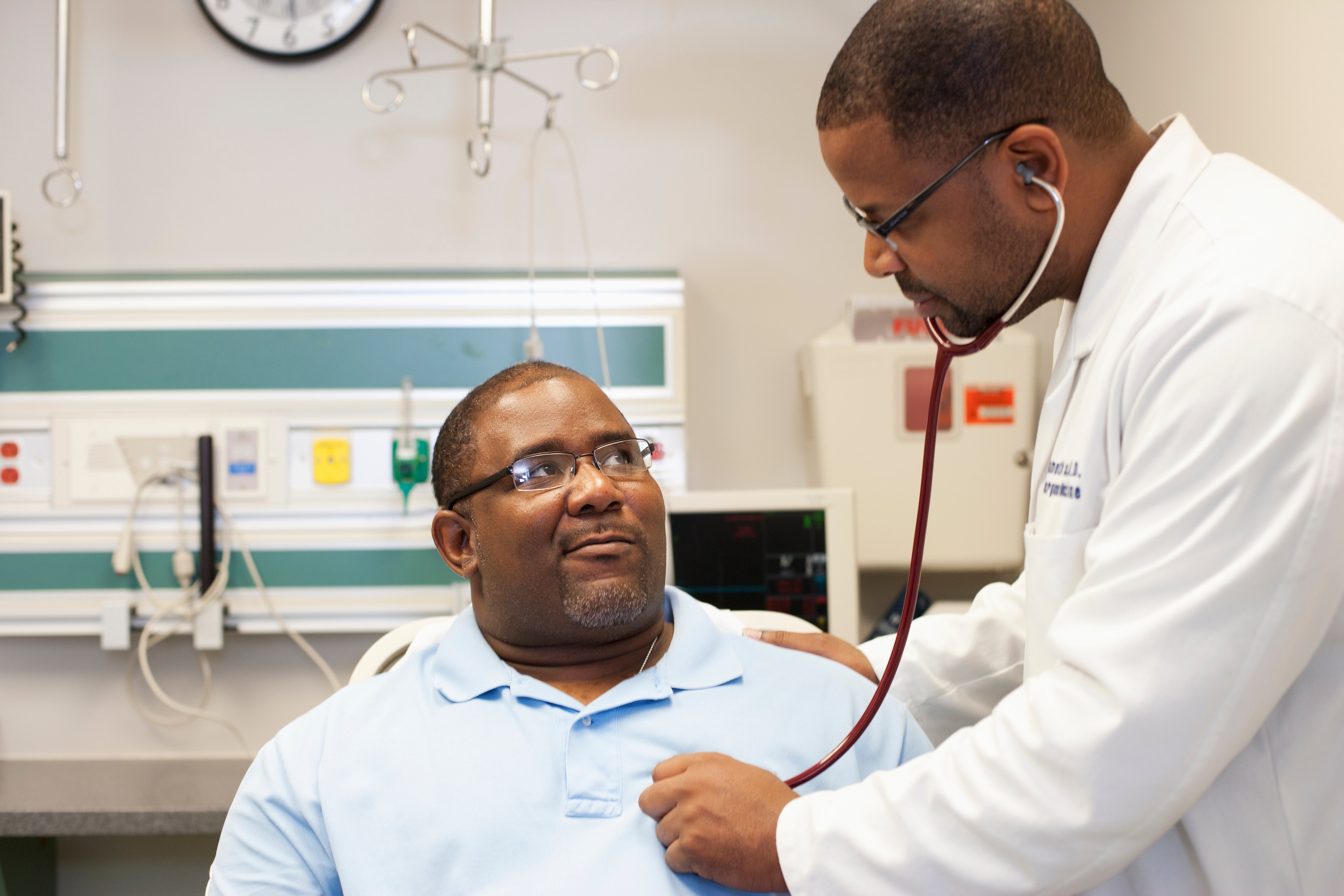 An overweight patient getting his heart checked by a doctor using a stethoscope