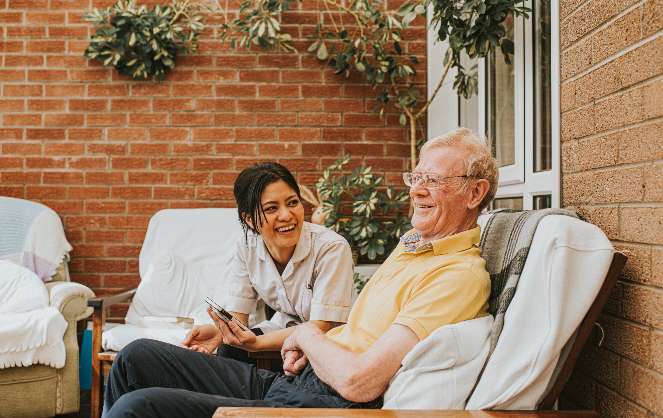 Home healthcare provider sits outside with patient