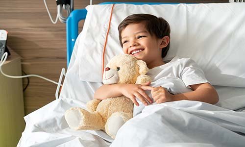little boy in hospital holds teddy bear