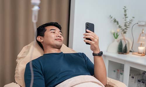 adult man looks at cellphone while getting an infusion