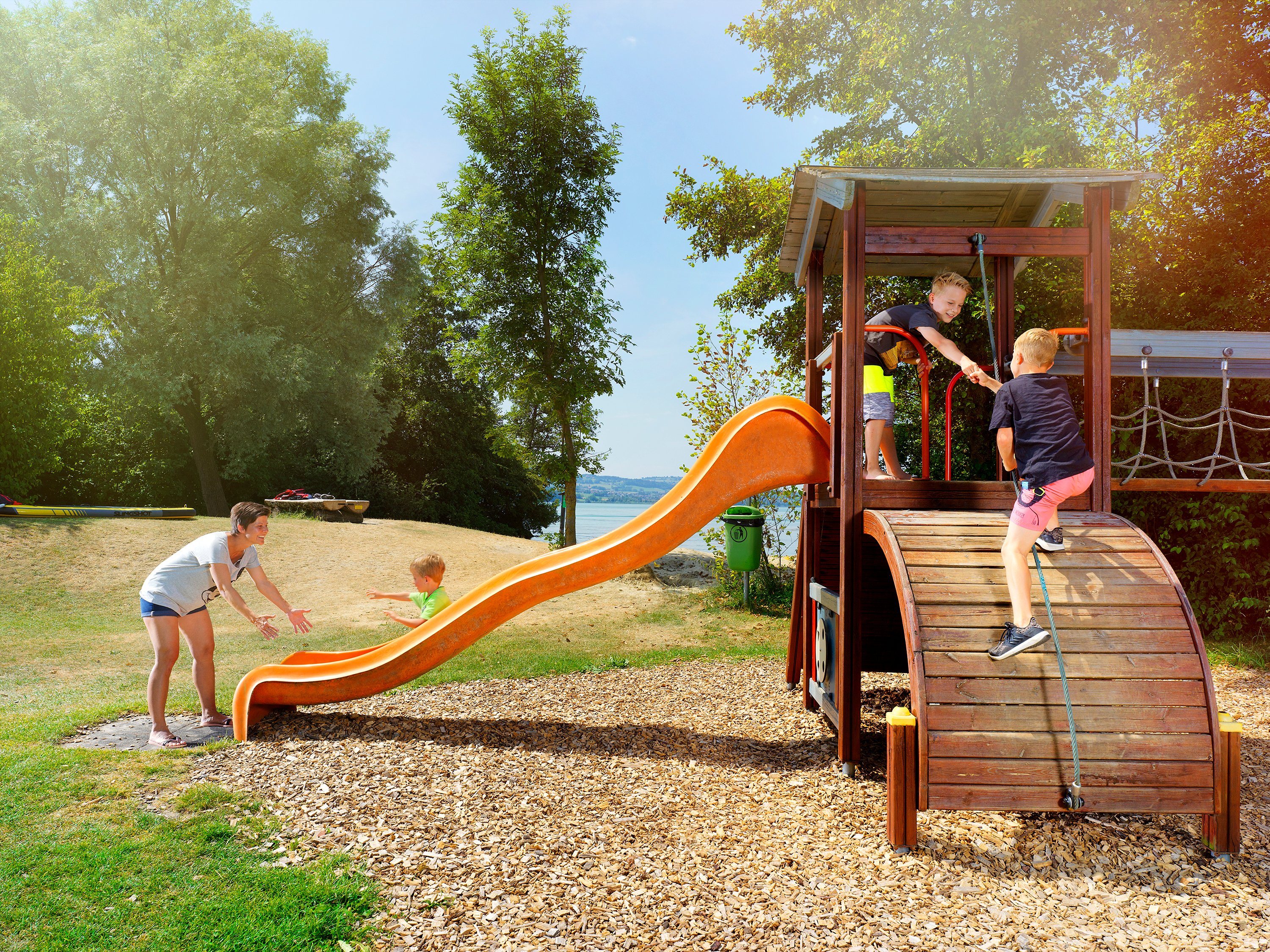 TCS Camping Sempach Familie spielt auf Spielplatz nahe am Wasser