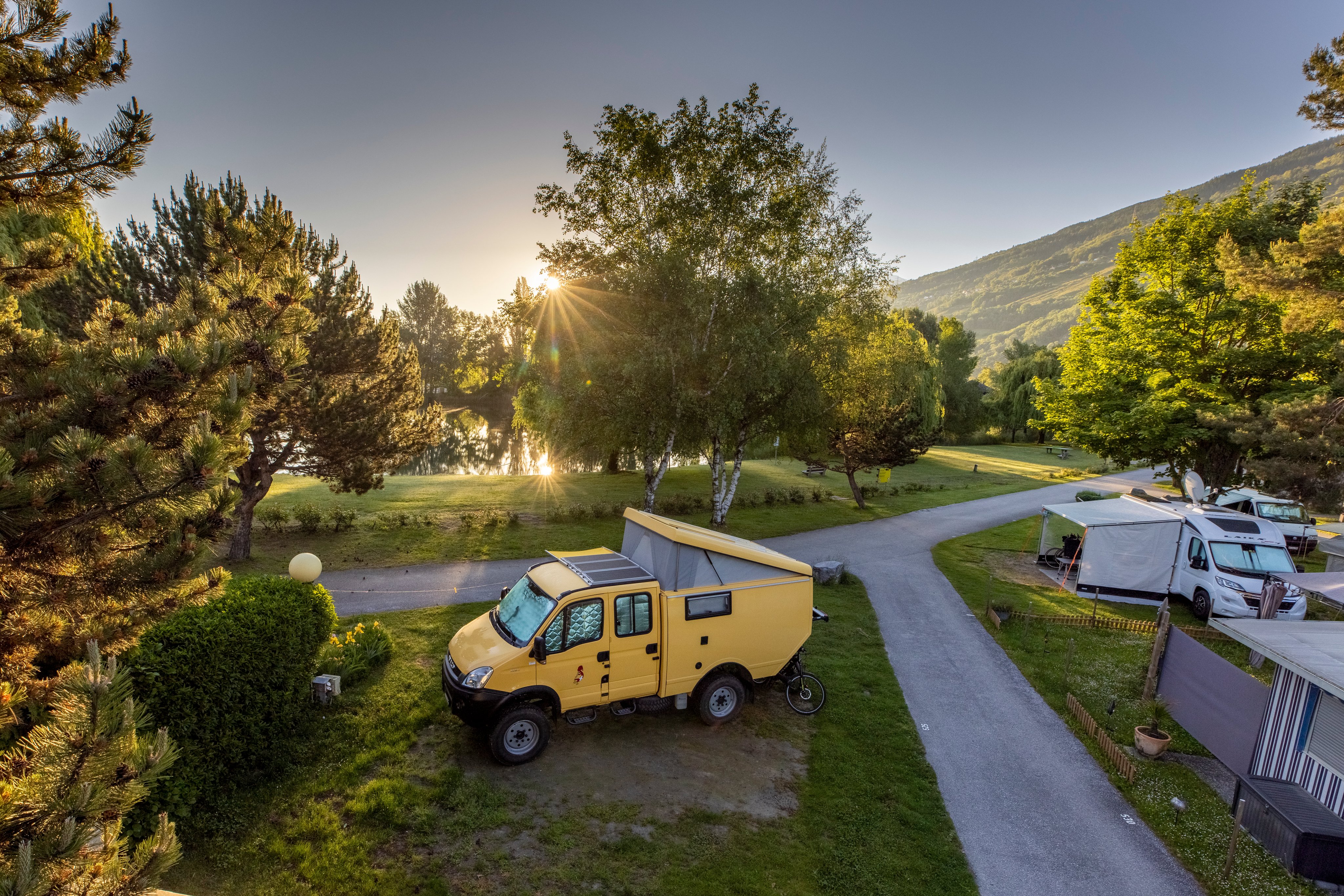 Un camping-car jaune se dresse sur un terrain de camping au lever du soleil.