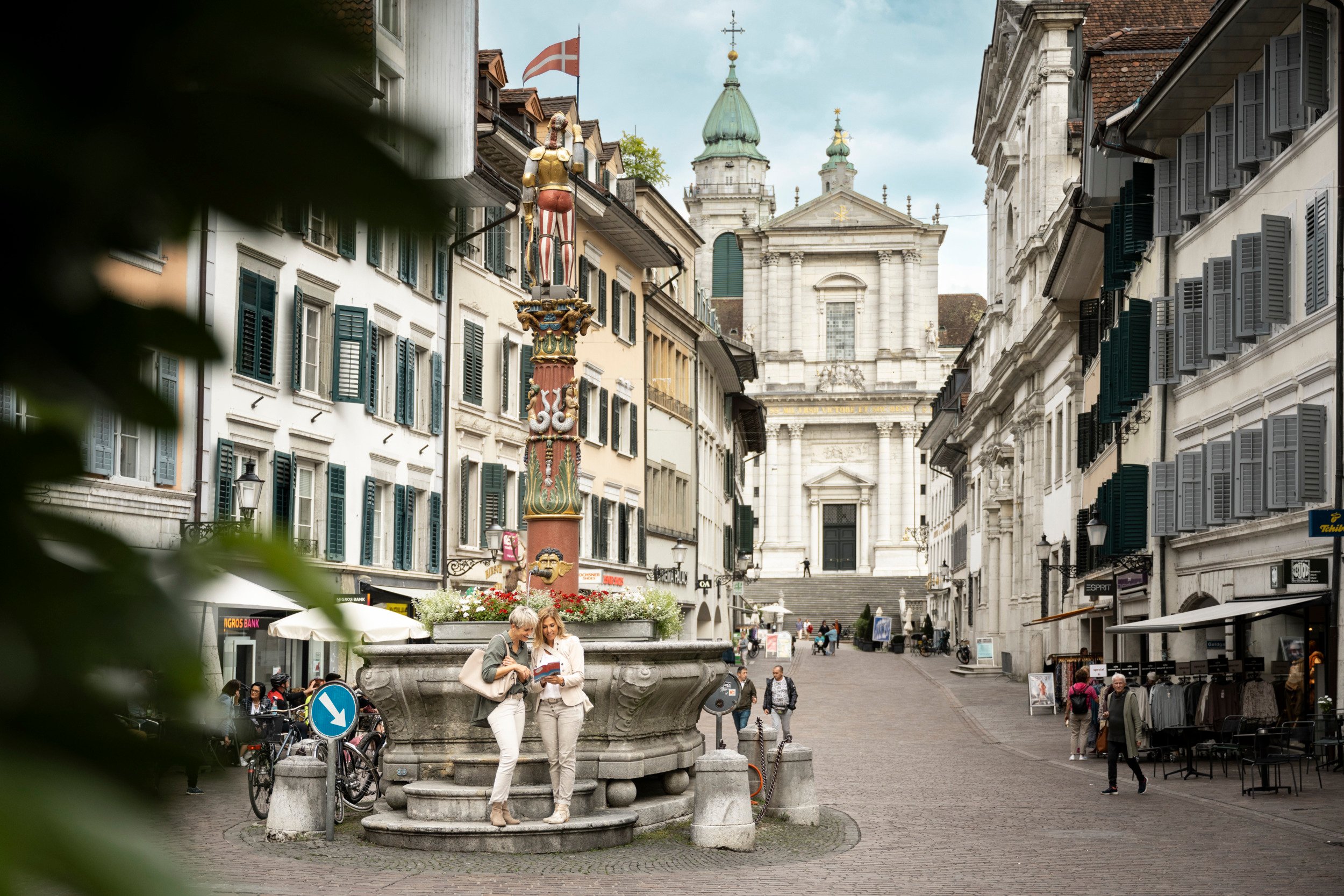 Deux femmes regardent la carte de la ville, avec en arrière-plan la cathédrale Saint-Ours à Soleure.